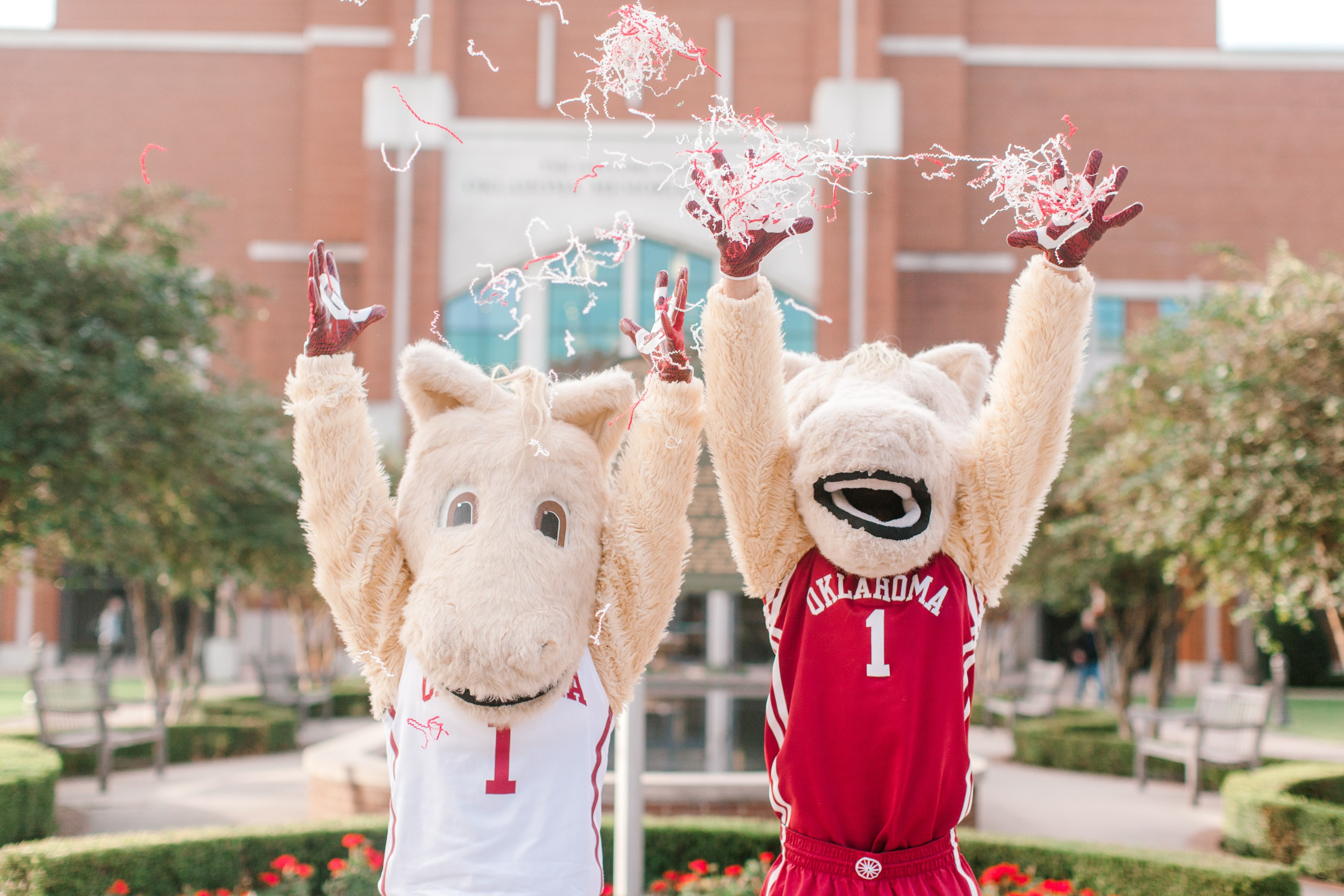 Boomer and Sooner mascots in OU jerseys throwing confetti.