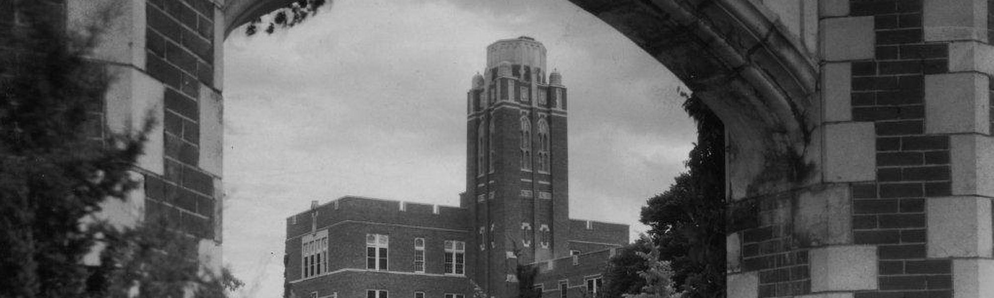 A black and white historical photograph of a building and archway on the University of Oklahoma Norman campus.