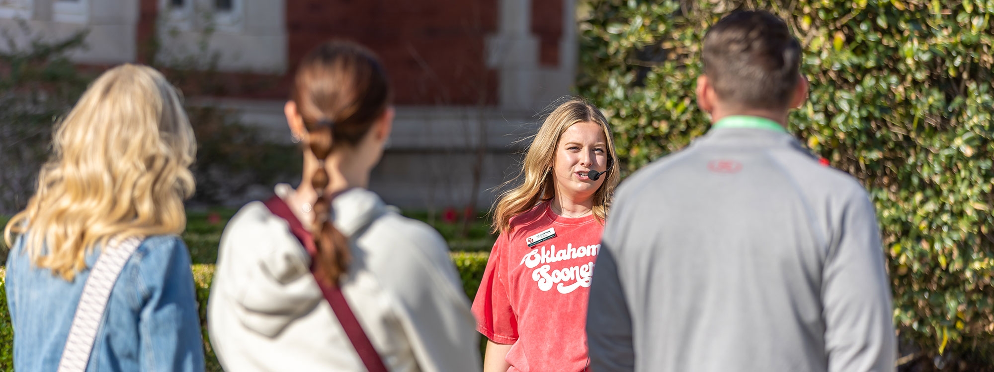 An OU tour guide walks with a group of visitors on the University of Oklahoma campus.