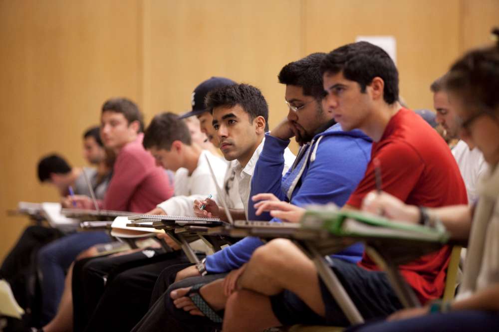 Students sit on the front row of a lecture hall taking notes