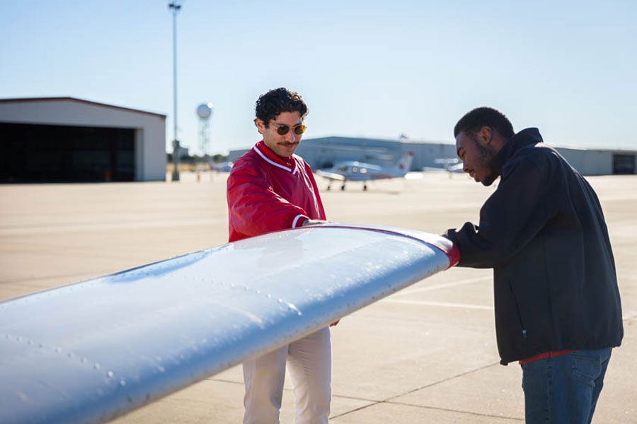 Two people working on an airplane wing.
