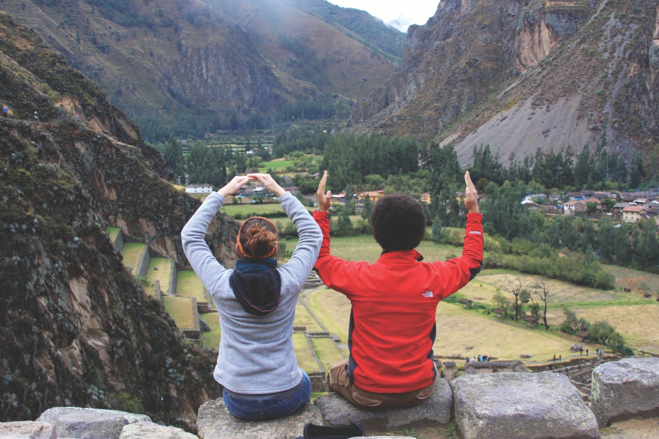 Students sitting on a hill in front of mountains.