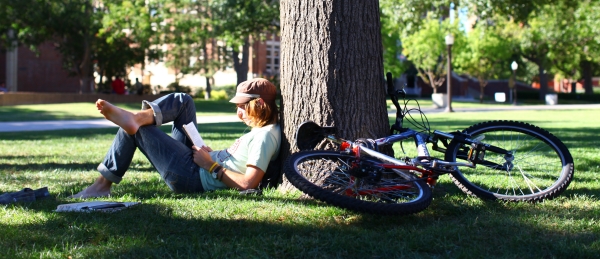 student reading leaned against a tree