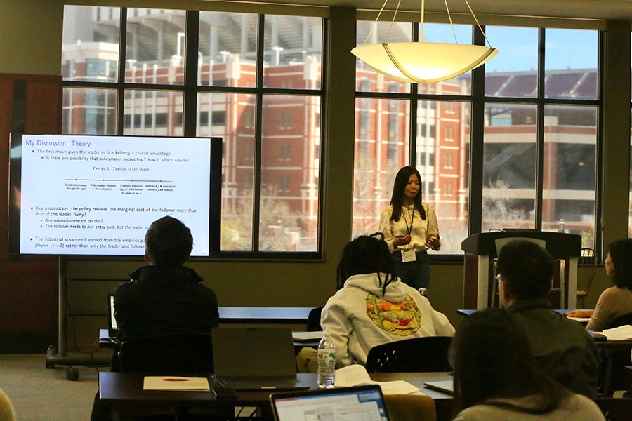 Someone in front of a window lecturing to a group of students. 