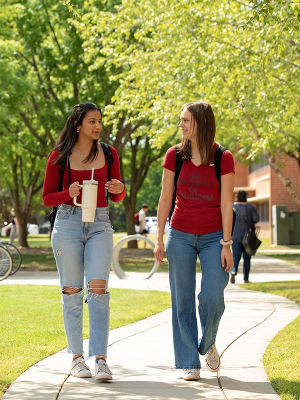 Two students walking outside on a winding sidewalk.