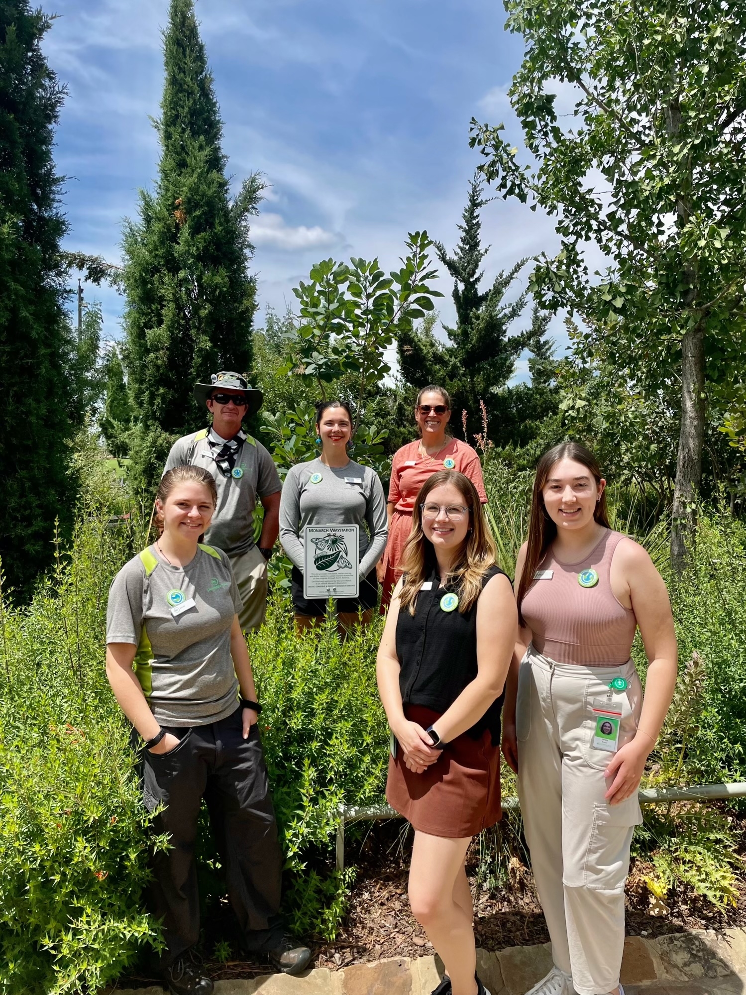 Six people pose for a photo in a grassy park location