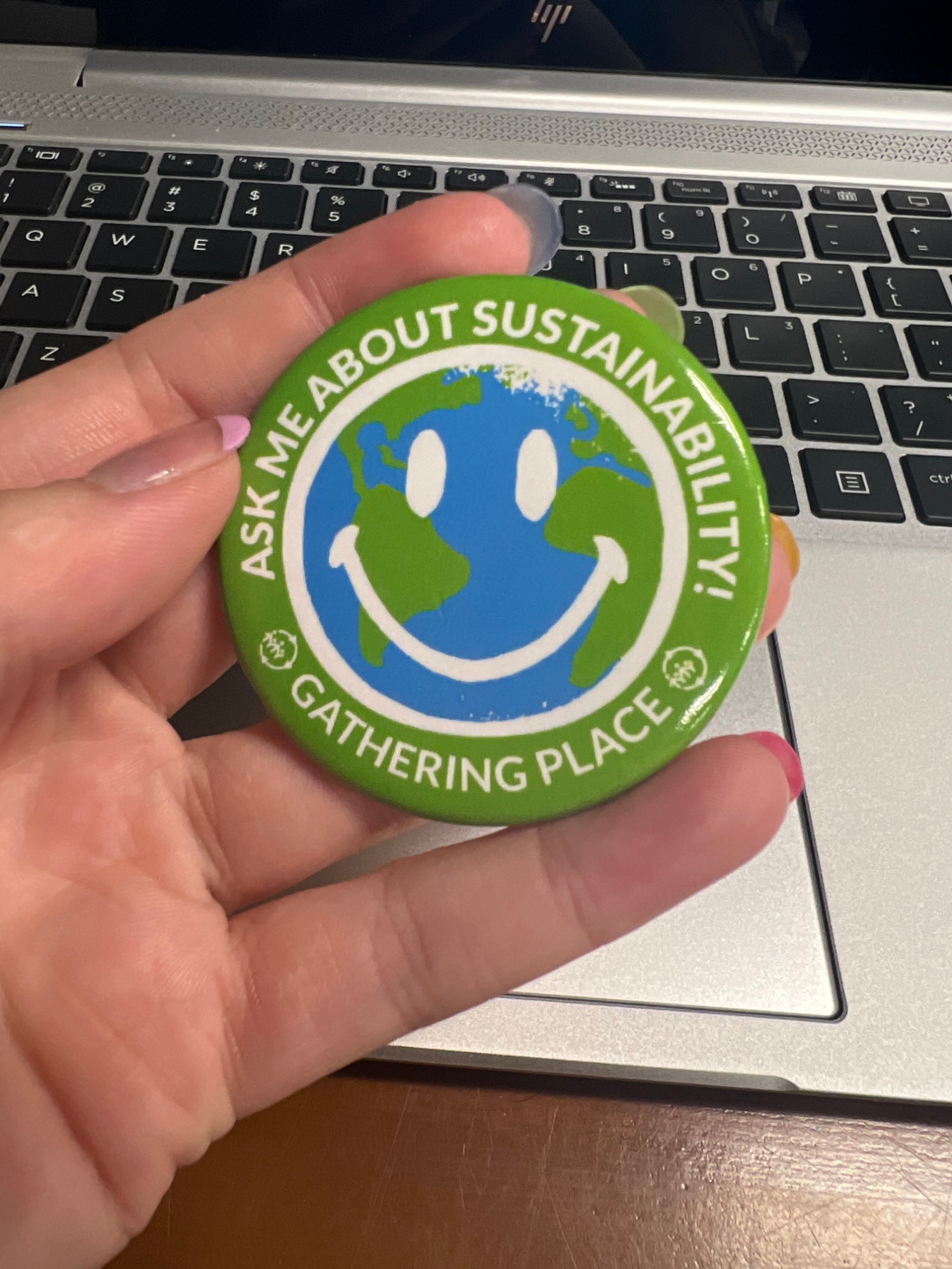Student holds a Gathering Place button in front of a laptop