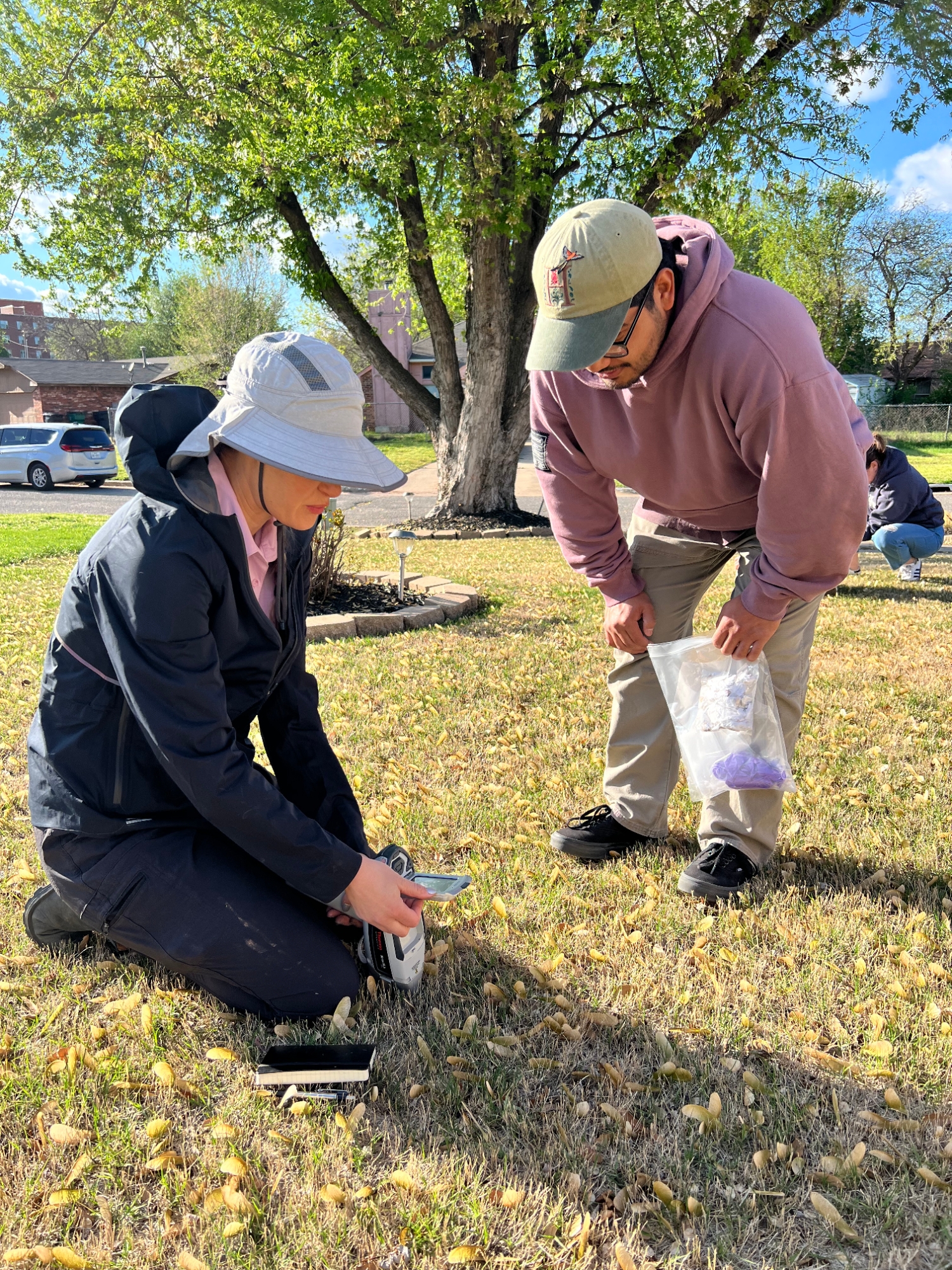 Two people test soil from a front yard