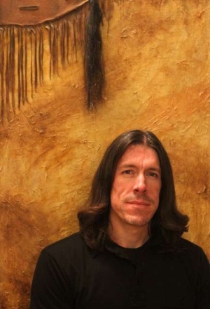 Josh Clough standing in front of a yellow painted background.