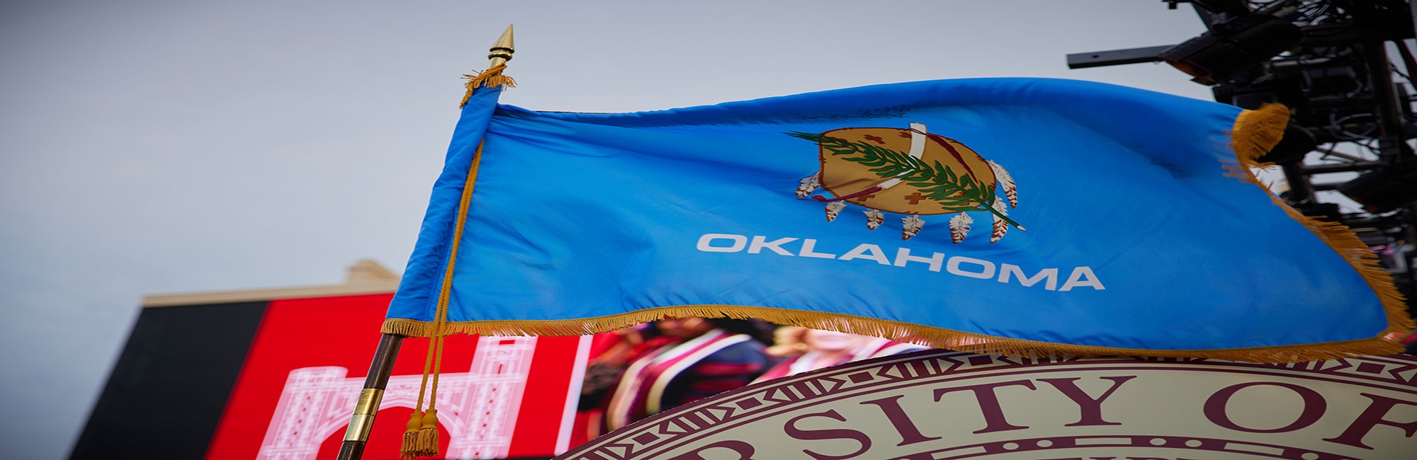 Gaylord Family Oklahoma Memorial Stadium megatron sign stating There's only ONE and State of Oklahoma flag in foreground.