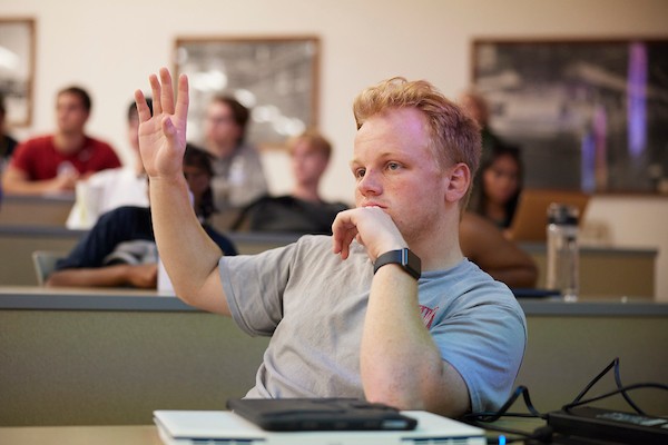 Student raising hand in a classroom.