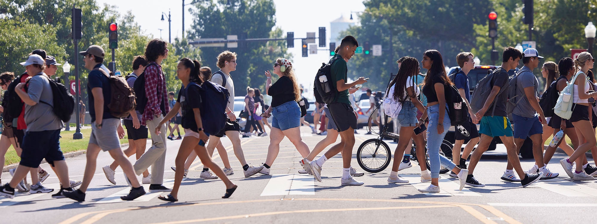 A busy street view of students crossing at crosswalk.
