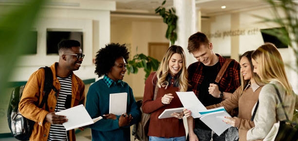 Happy female student showing test results to her friends while standing in a lobby.