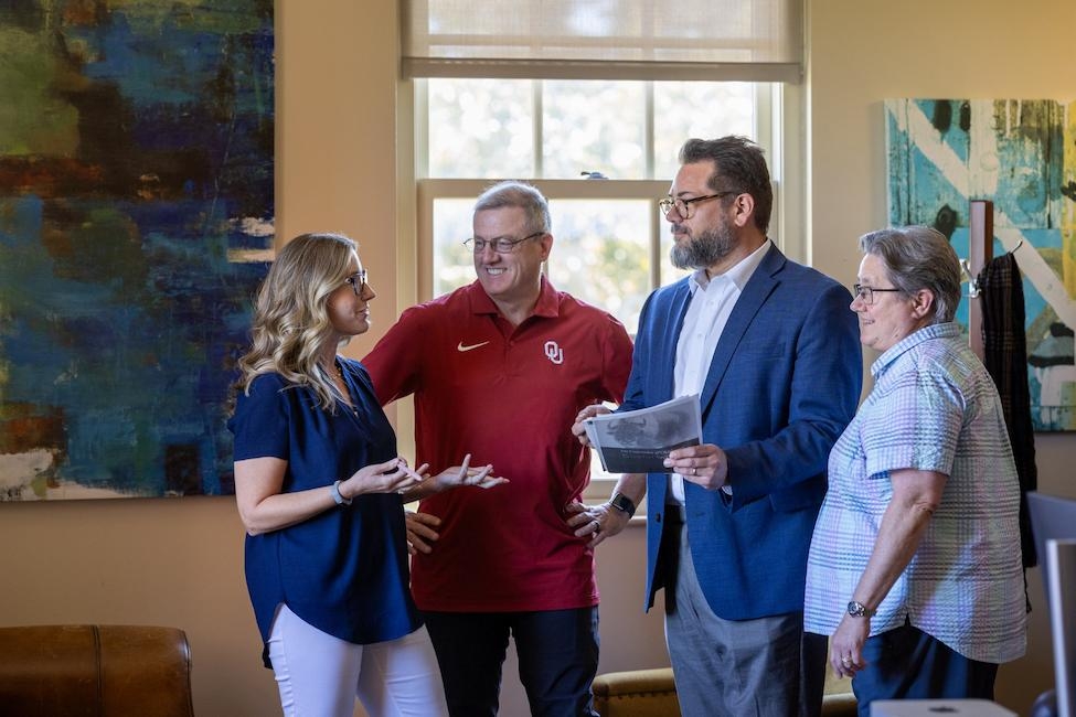 Four people stand in Zarrrow Hall having a discussion. The people are Christina Miller, David Dickerson, David McLeod, and Charlotte Kendrick.