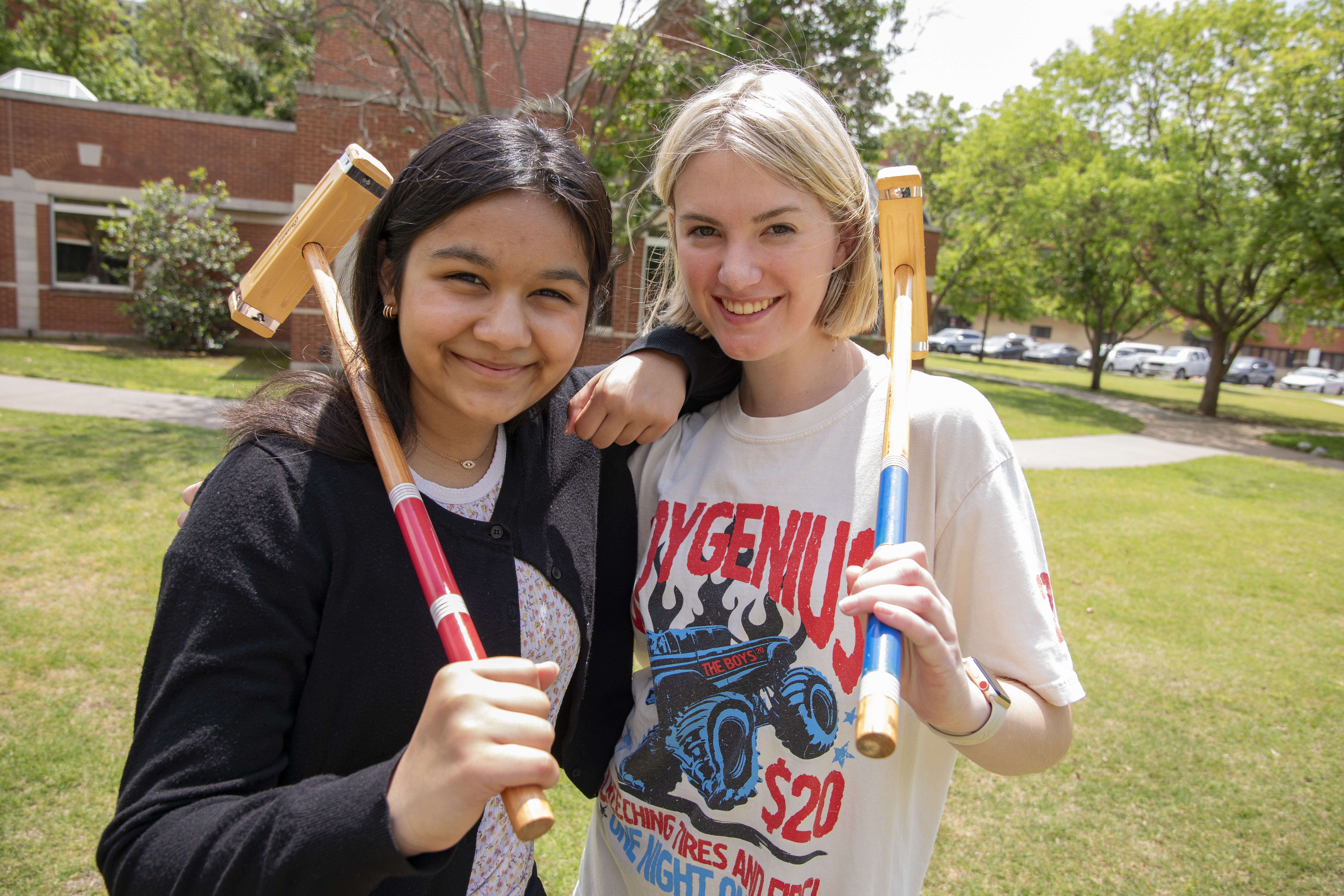 Two students holding mallets and smiling. 
