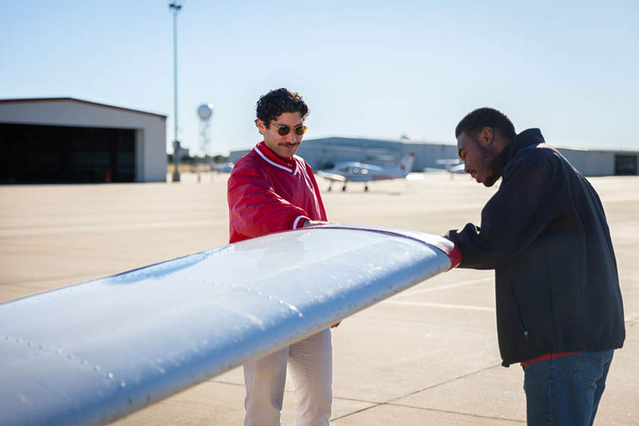 Two people inspecting the wing of an O U aircraft.