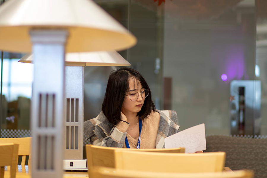 student studying quietly at a work table with a lamp nearby.
