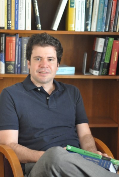 A photo of 布鲁诺Uchoa sitting in front of a bookcase.