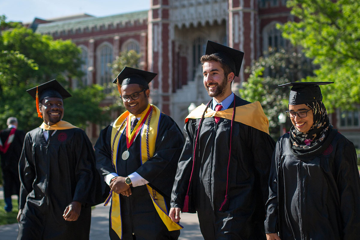 OU graduates walking around campus in caps and gowns before the ceremony.