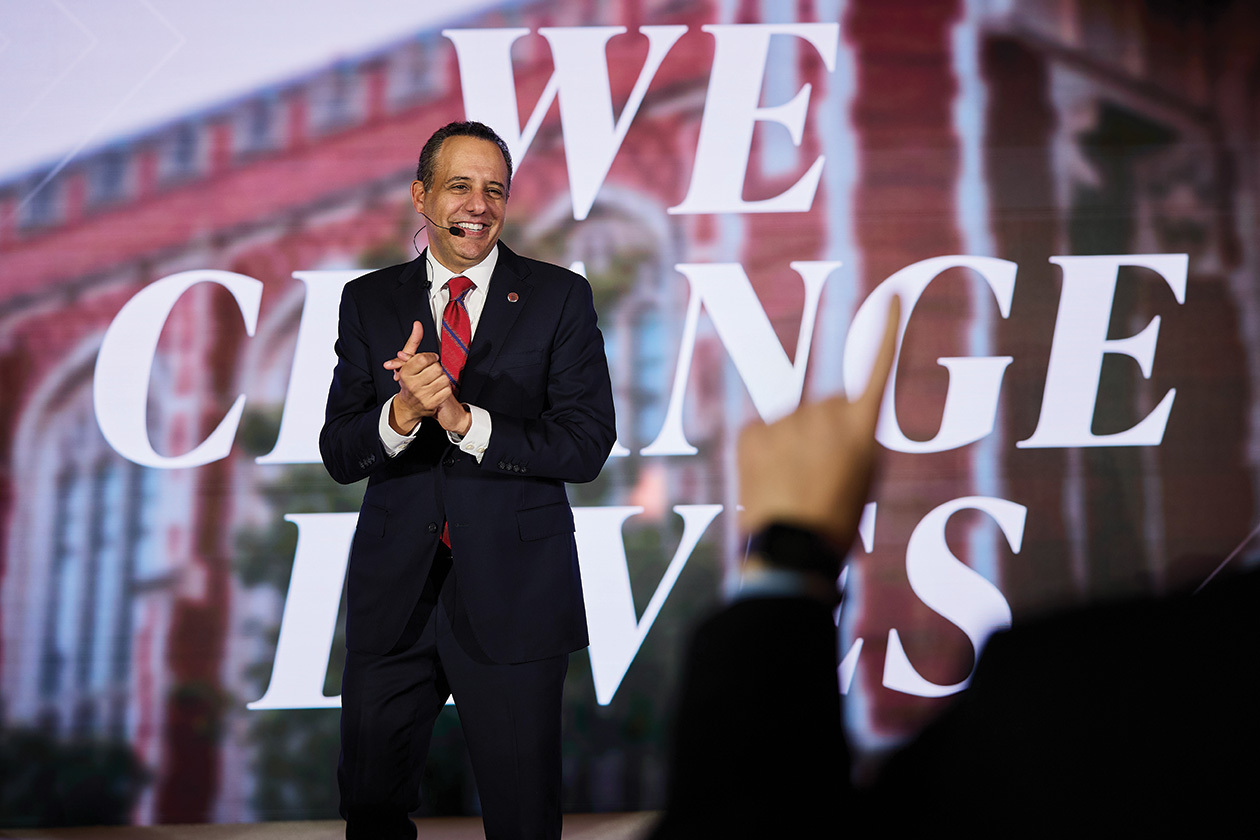 President Joseph Harroz in front of a screen that says "We Change Lives".