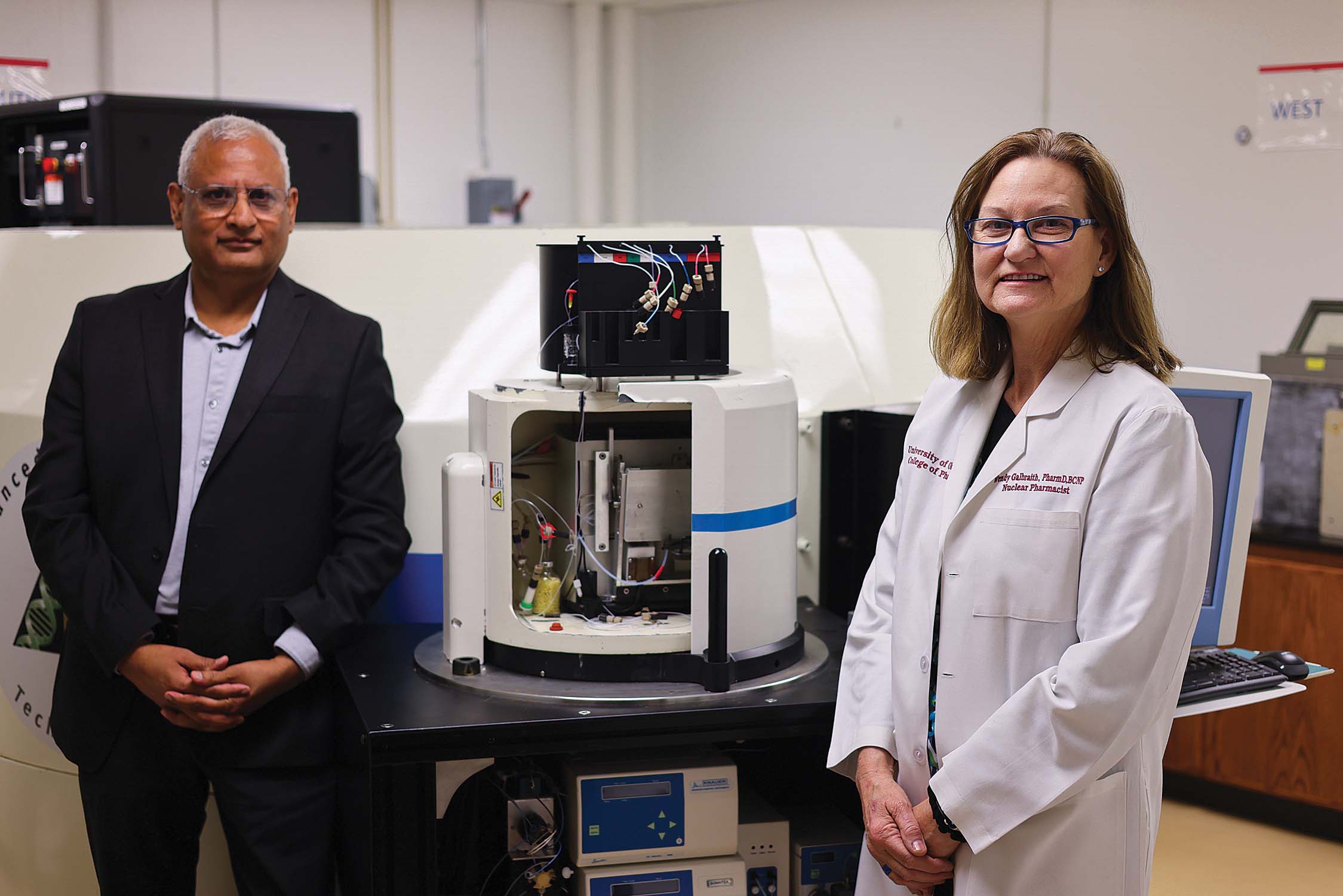Two people standing on either side of a cyclotron.