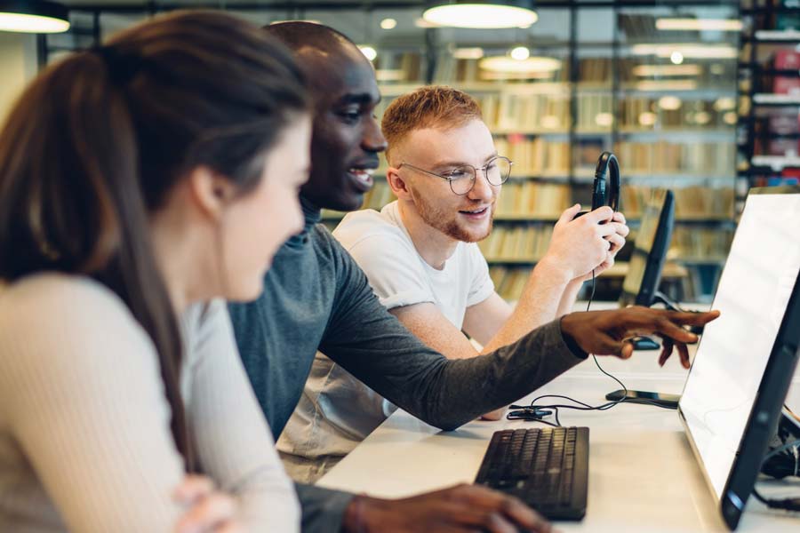 Three people collaborating together around a computer. 