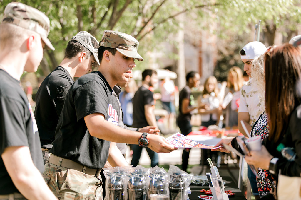 ROTC cadets passing out fliers at a booth to students on the South Oval.