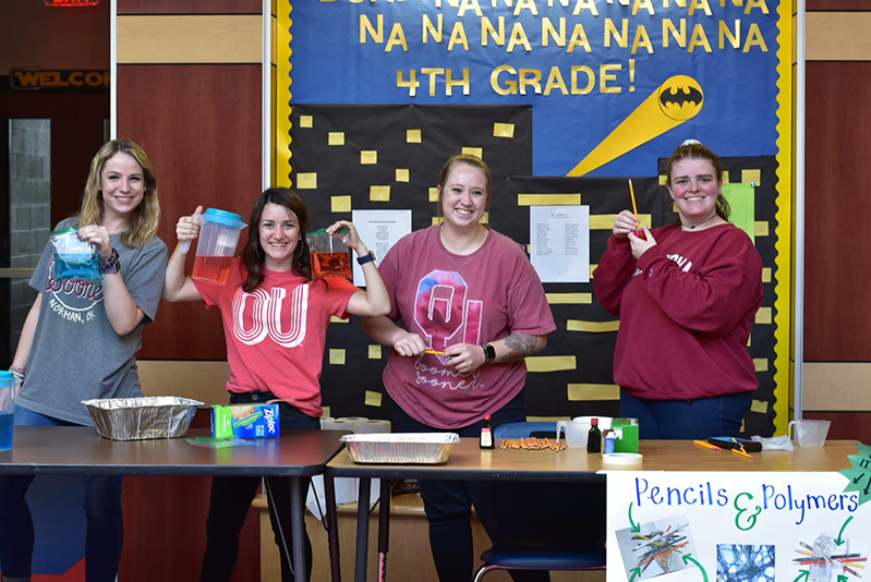 Students standing at table holding science experiment tools