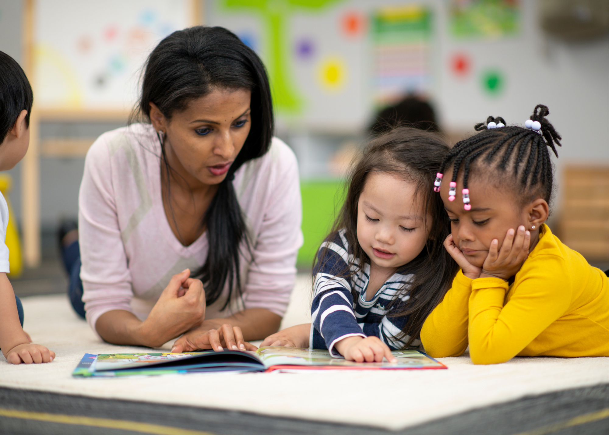 Woman sitting with two kids at a table as they read books