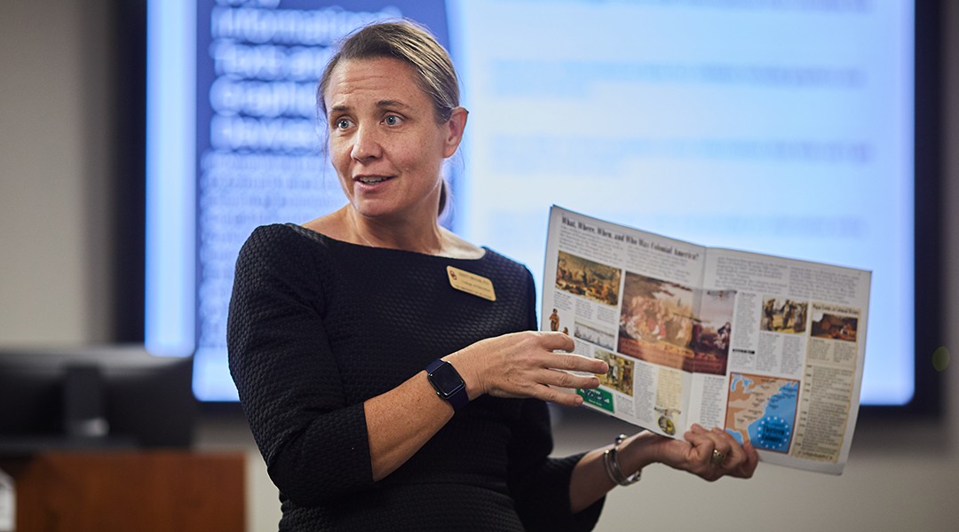 OU professor showing magazine and talking to class.