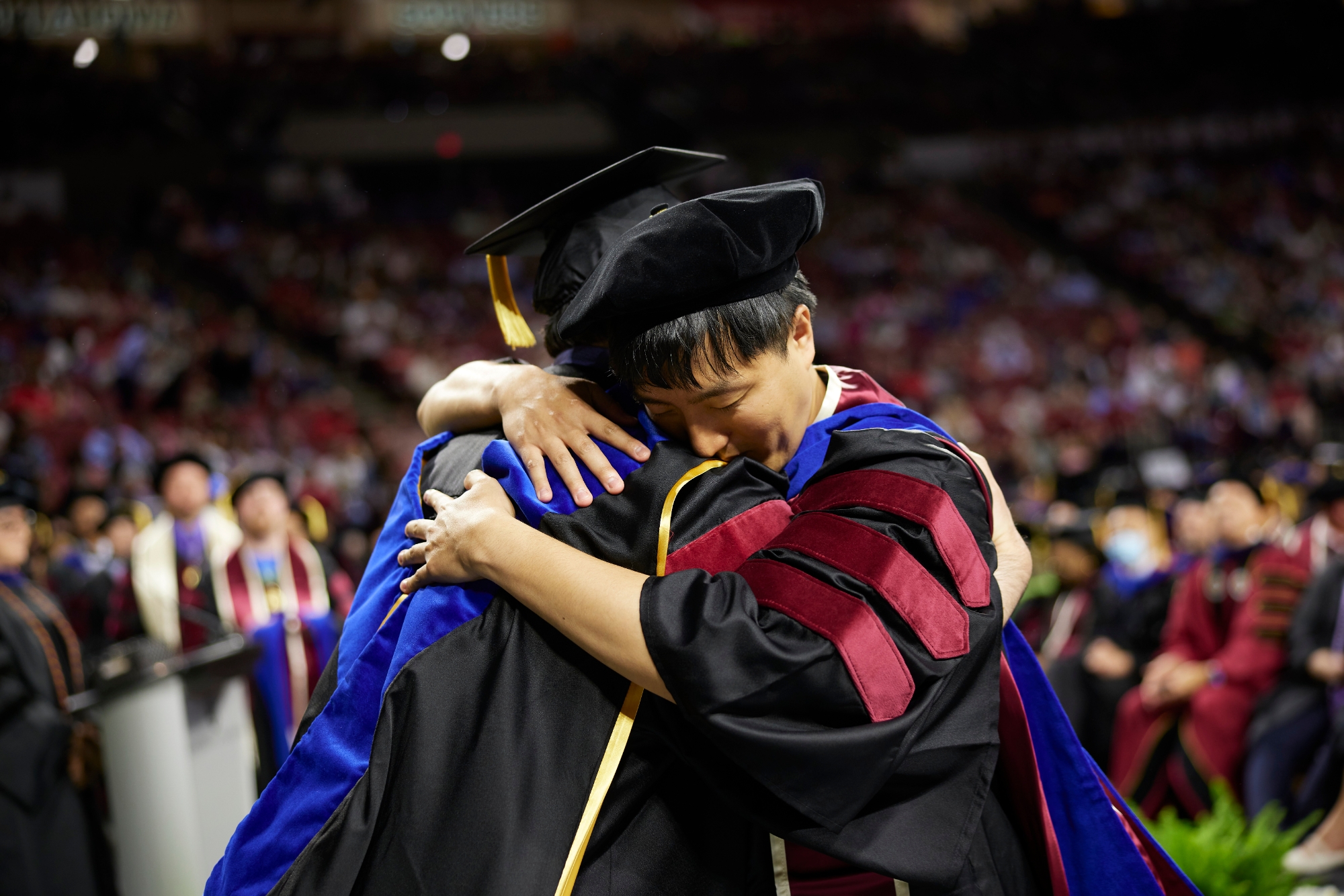 Two graduates hug.
