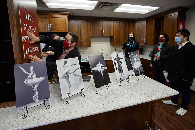 OU staff member places "5 Moons Student Lounge" sign at socially distanced, masked ceremony