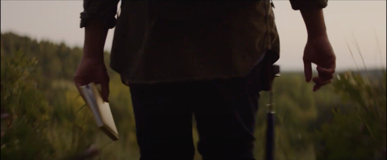 Delcio walking in field with a journal.