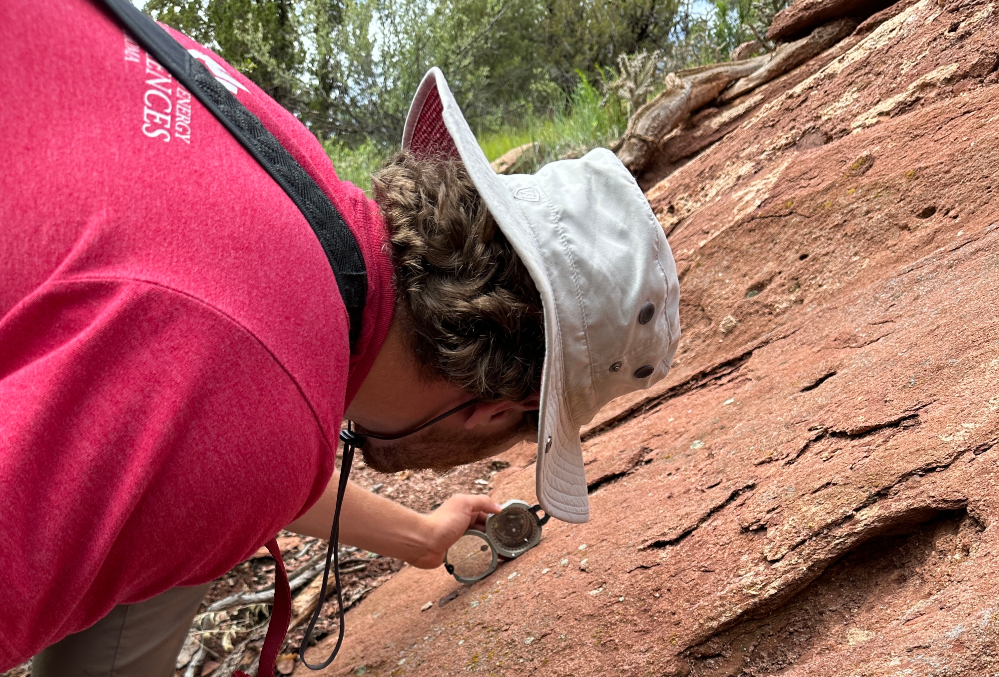 A student using a compass on a rock.