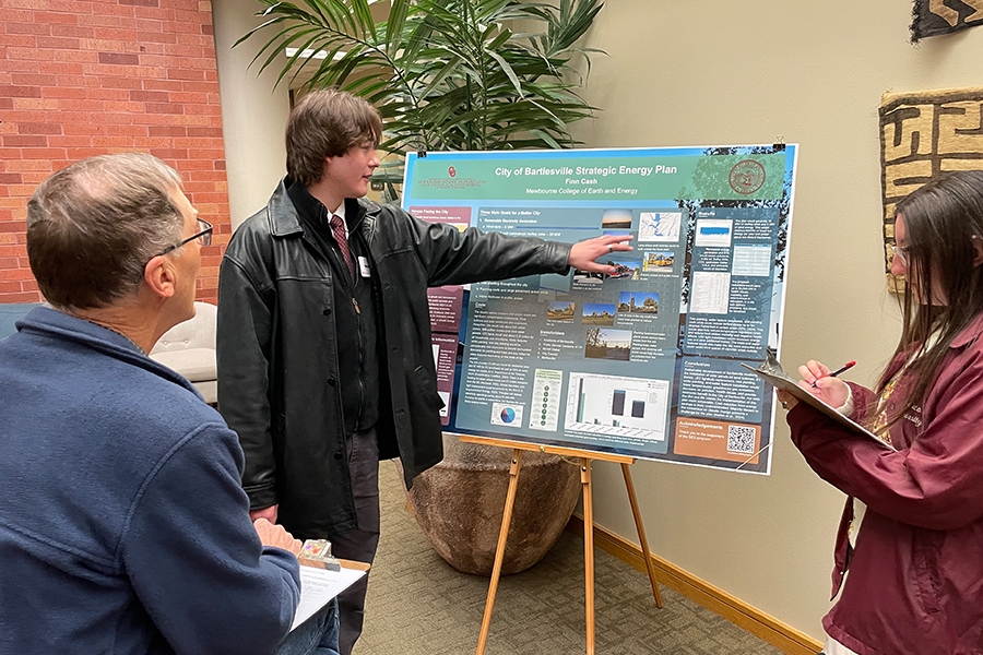 SES poster presentation with one student presenting to two people.