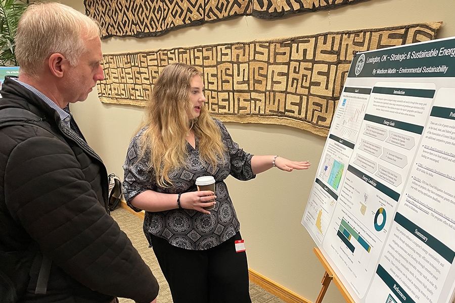 A student looking presenting her poster to a faculty member.