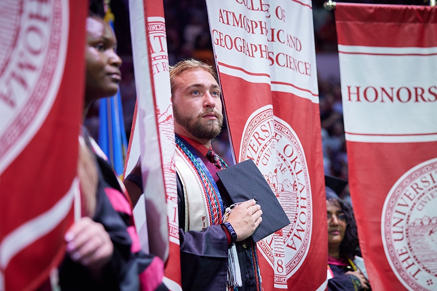 Marcus Ake, a graduate from the OU College of Atmospheric and Geographic Sciences, proudly displays the college’s banner.