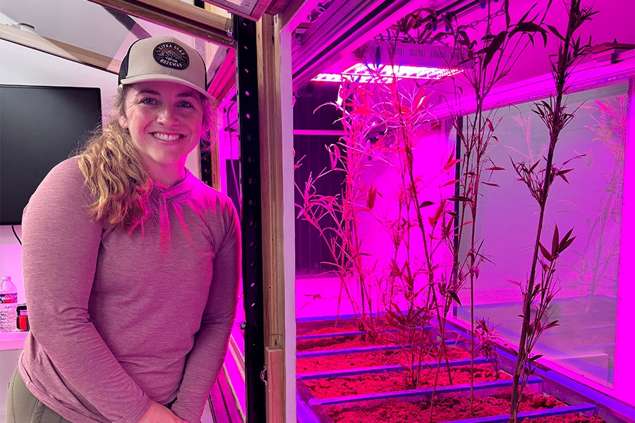 Hailey Seago standing next to plants growing beneath a grow light.