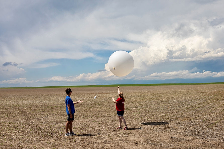 School of Meteorology students releasing a weather balloon in an empty field.
