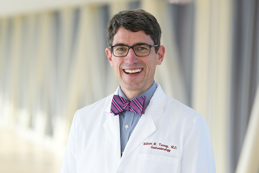William M. Tierney smiling in his doctor's coat, standing in the OKC skywalk.