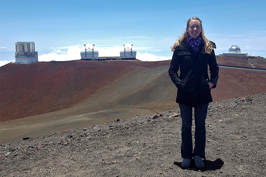 Nielsen standing on Mauna Kea in front of the Subaru Telescope, the twin W. M. Keck Observatory telescopes, and NASA IRTF.