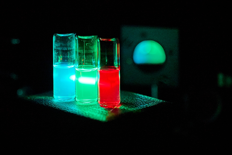 Synthesized quantum dots suspended in solvents under laser irradiation.