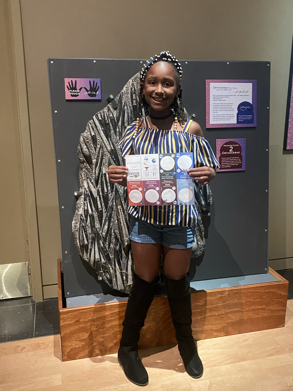 Girl Scout Aleigha O. poses with some orthoceras fossils and her completed Mass Extinction Passport Book!