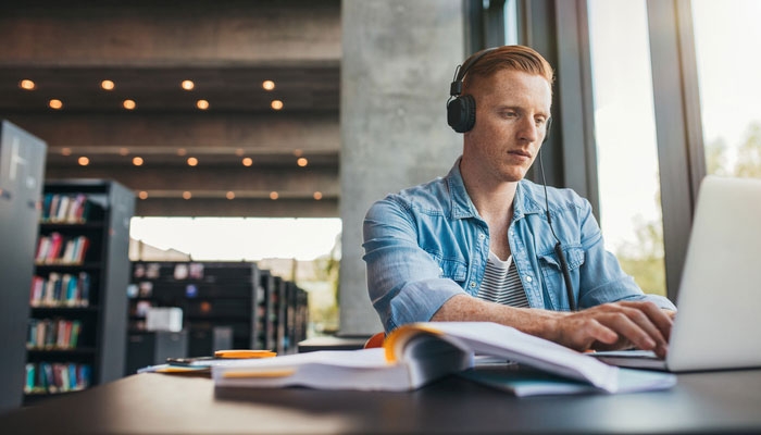 students using laptop and wearing headphones in the library