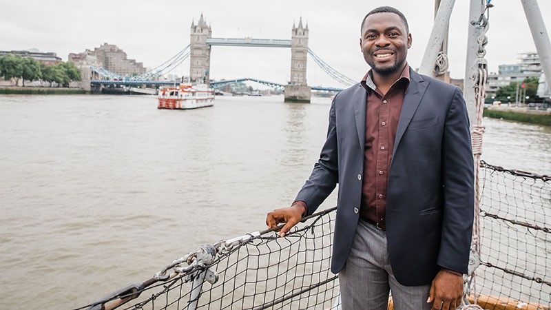 能源行政工商管理硕士 student pictured on a boat on the River Thames with London Bridge in the background.