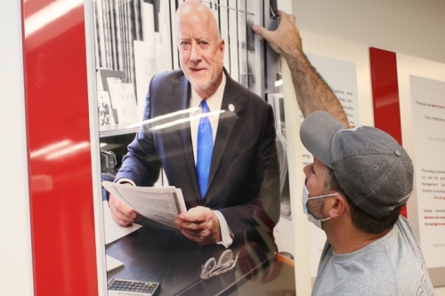 Man hanging photo in the Robert M. Zinke Energy Management Program Collaborative Classroom