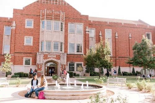 Two students sit by the fountain near Price Hall