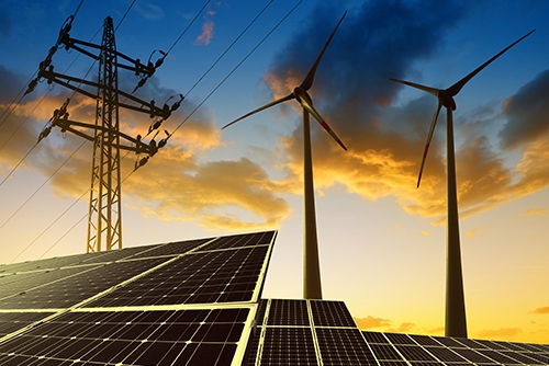 blue and orange sky as the sun sets against a row of solar panels and wind turbines