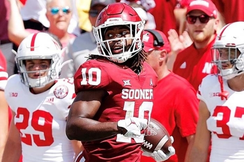 Sooners football safety Pat Fields runs with the football as fans and team members look on