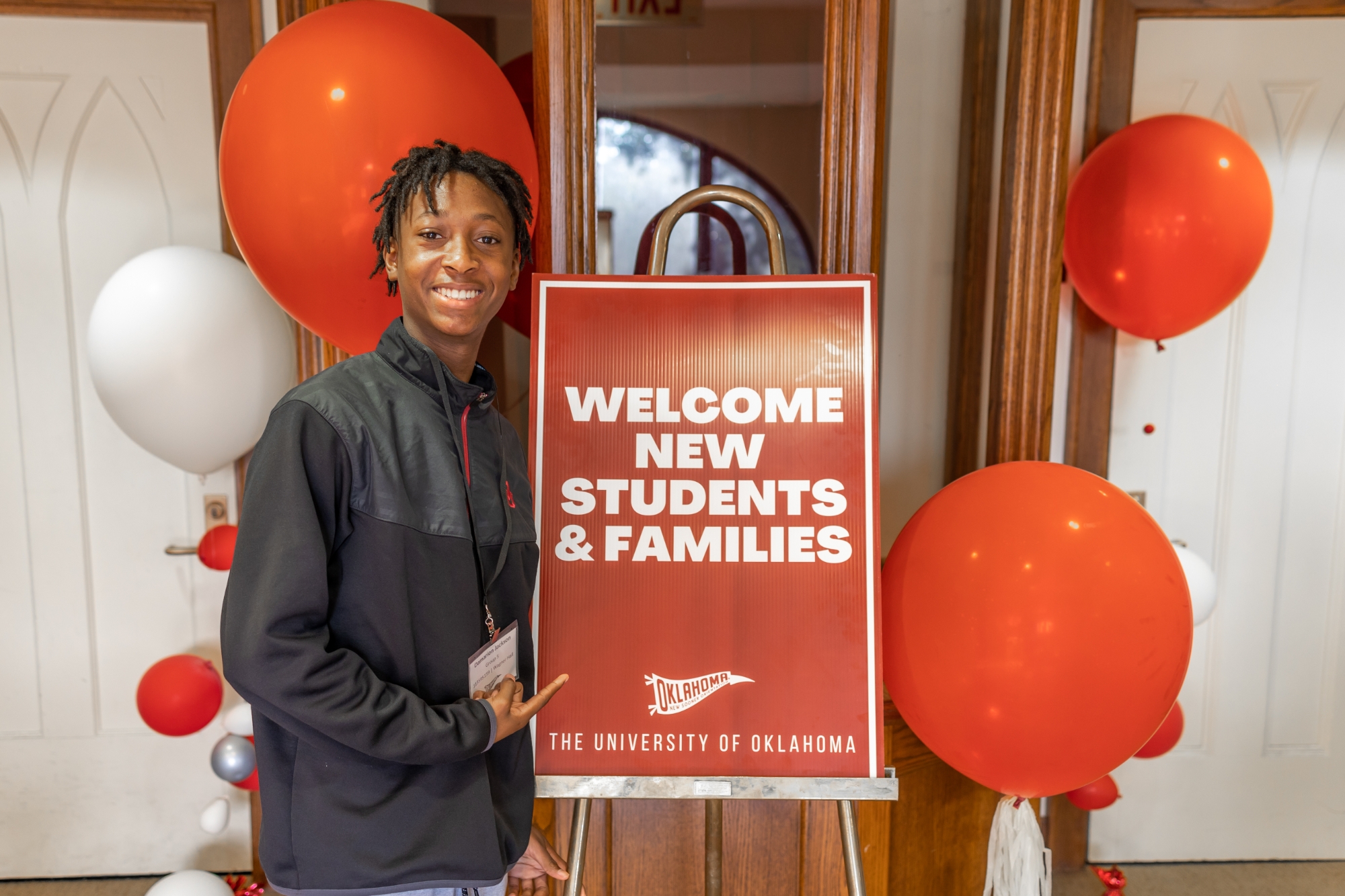 Student posing with New Sooner Orientation sign